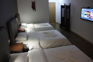 Una habitación de hotel con dos camas, televisión, armario y una mesita.