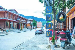 A street with traditional buildings, a tree with a tire swing, and parked motorcycles.
