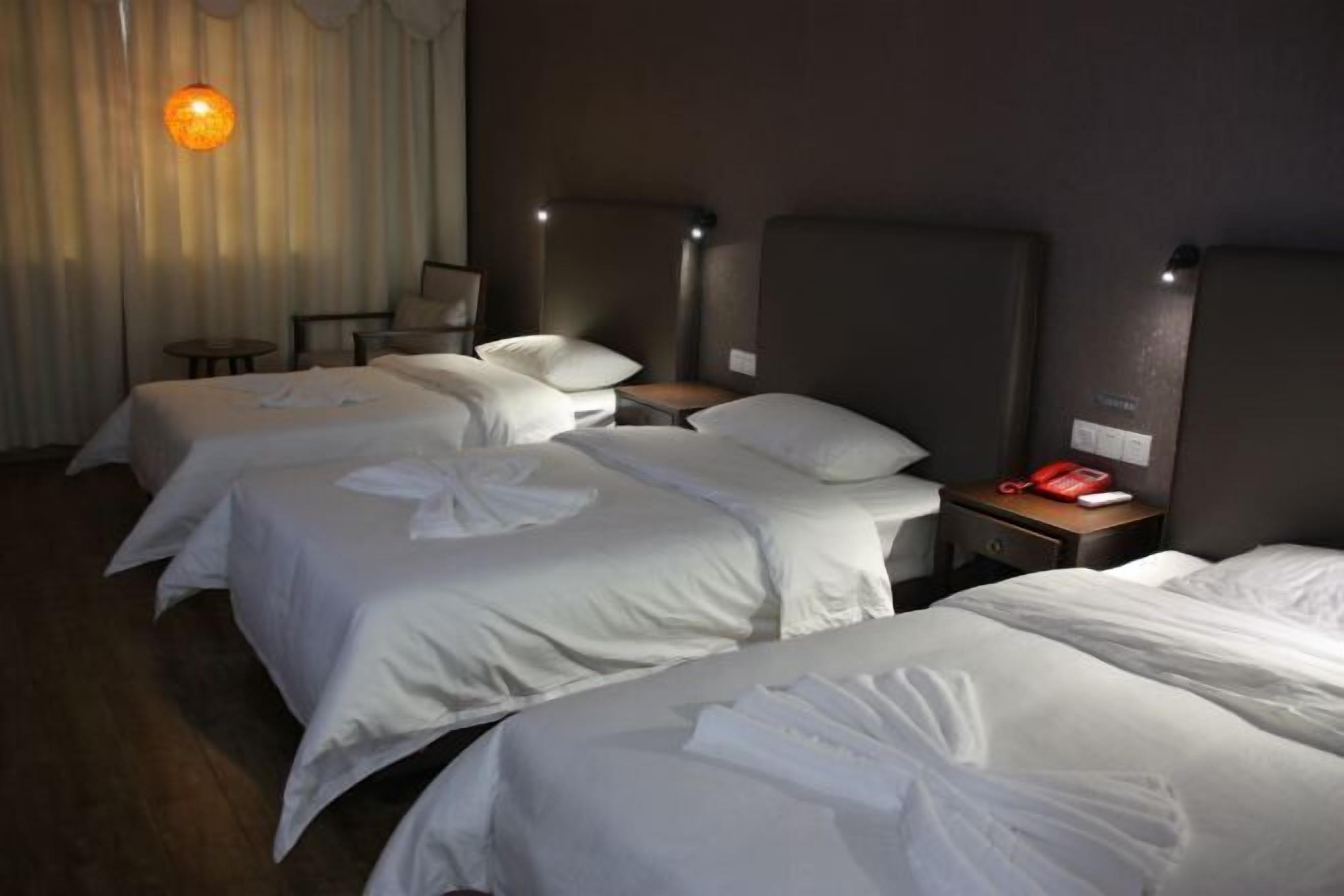 Una habitación de hotel con tres camas, un escritorio y una silla.