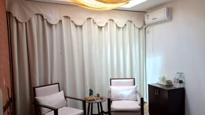 A room with two chairs, a small table, a cabinet, and a curtain. - Luguhu Aishang Hotel (Ninglang)