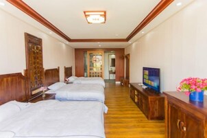 Habitación de hotel con dos camas, un televisor, un armario de madera y un pasillo que lleva al baño.