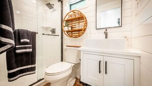A modern bathroom with a toilet, a sink, and a shower. - Moss Oak - Container Home Near Magnolia and Baylor (Waco)