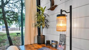 A wooden desk with a laptop, a potted plant, and wall-mounted bird sculptures. - Moss Oak - Container Home Near Magnolia and Baylor (Waco)