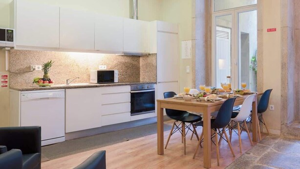 A modern kitchen with white cabinets, a microwave, and a dining area with a wooden table and chairs.