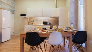 A modern kitchen with white cabinets, a microwave, and a granite countertop. There is a dining table set with plates, glasses, and a fruit bowl.