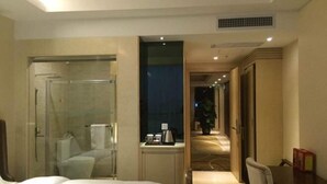 Una habitación de hotel con cama, ducha, escritorio y una silla.