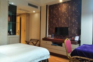 A hotel room with a bed, a desk with a computer, a chair, and a TV. - Joy Hotel (Fengkai)