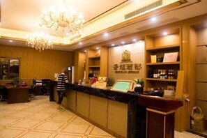 A hotel reception area with a marble counter, a chandelier, and a sign with Chinese characters. - Joy Hotel (Fengkai)