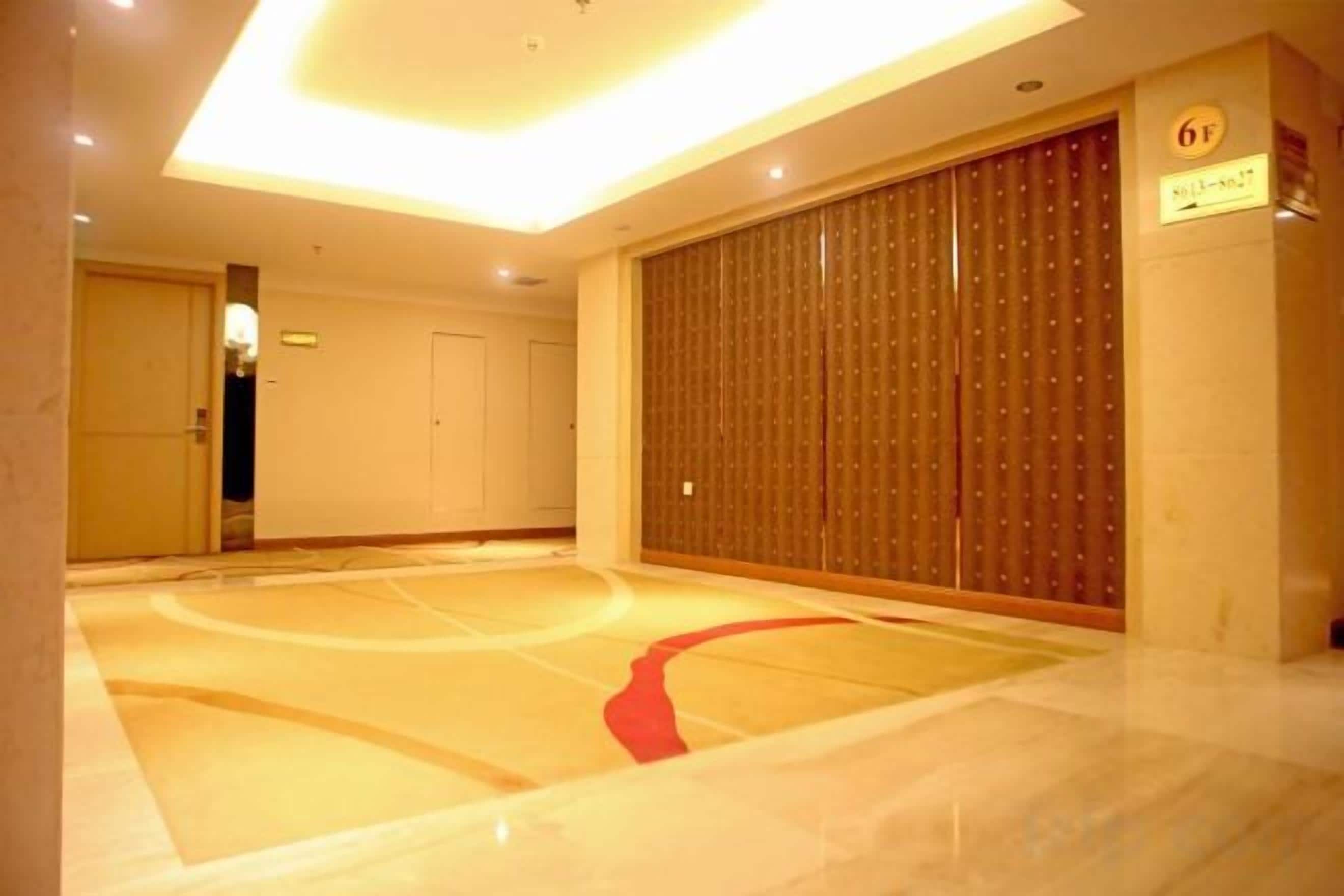 Habitación de hotel con un espejo grande, un armario de madera y una alfombra roja que conduce a la puerta.