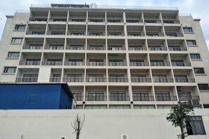 A multi-story building with balconies, a flat facade, and a blue structure to the left. - Joy Hotel (Fengkai)