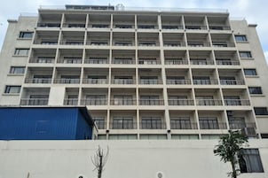 Un immeuble à plusieurs étages, doté de balcons, d’une façade plate et d’une structure bleue sur le côté gauche.