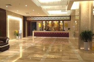 A spacious lobby with a reception desk, a leather sofa, and potted plants.