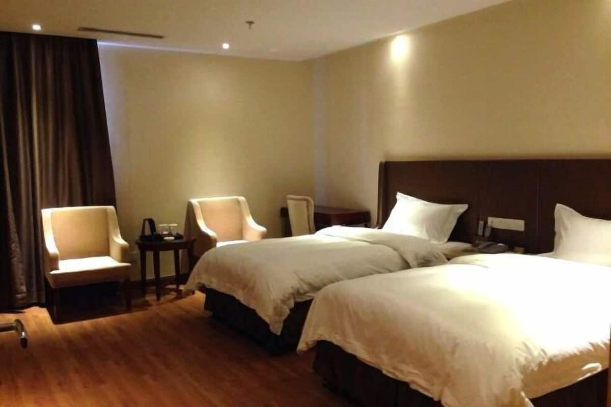 A hotel room with two beds, a chair, a small table, and a nightstand.