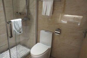 Un baño moderno con ducha de vidrio, inodoro y barra para toallas.