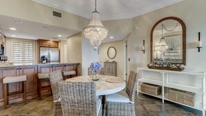 A dining area with wicker chairs, a round table, and a chandelier.