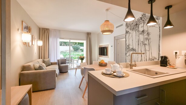 Una cocina moderna con una isla central, un comedor con mesa y sillas, y una sala de estar con sofá y mesa de centro.