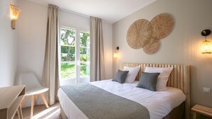 A bedroom with a bed, a desk, a chair, and a window with curtains.