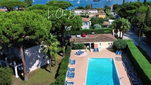 Un resort con piscina, sillas de descanso y vistas al mar y embarcaciones.