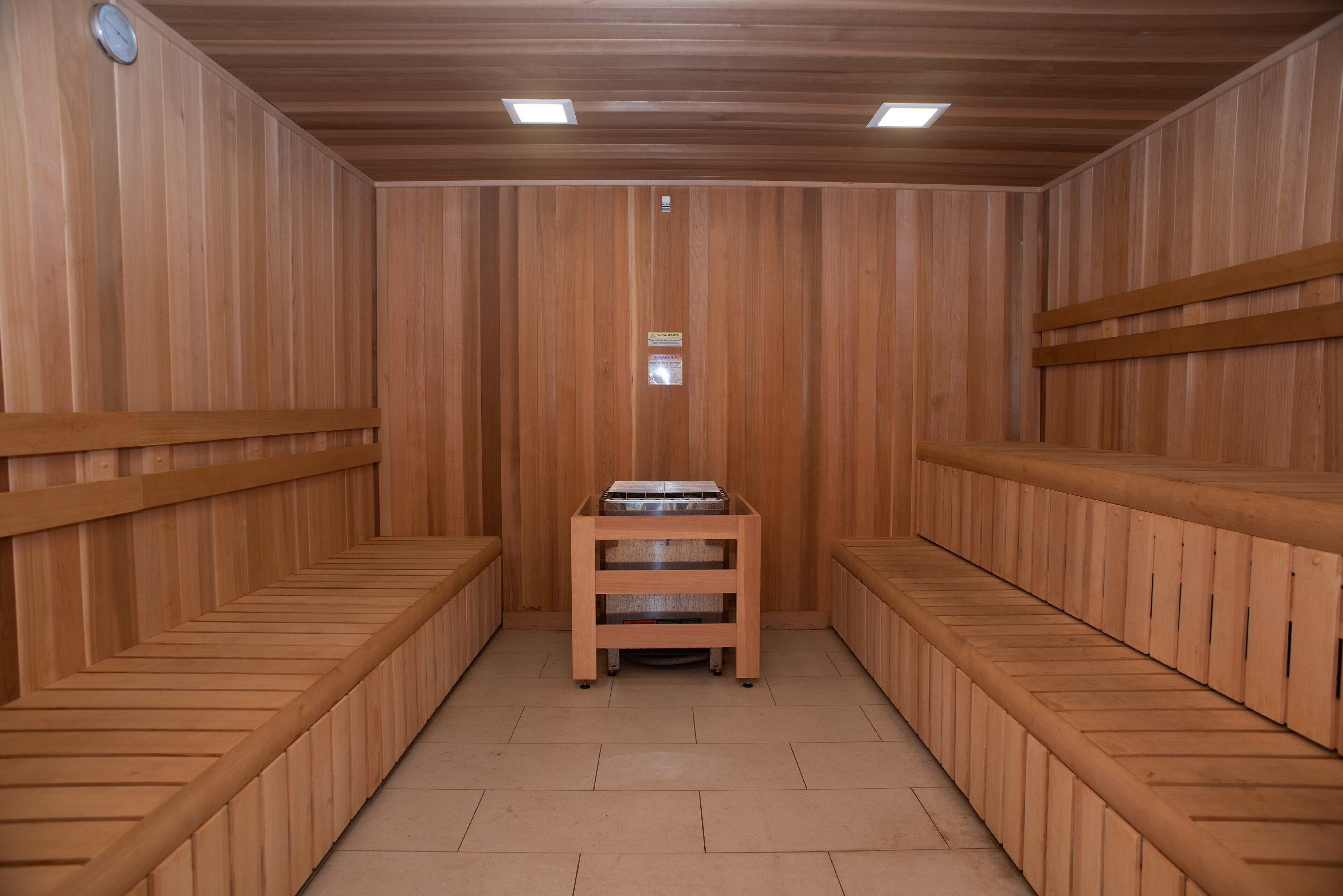 A sauna room with wooden benches and a central table.