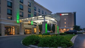 A hotel entrance with a covered walkway, a stone facade, and a parking area.