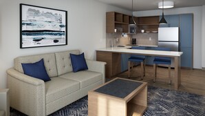 A modern living room with a sofa, a coffee table, and a kitchen area with a dining table and bar stools.