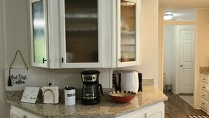 A kitchen with white cabinets, a coffee maker, a sugar container, and a framed sign. - Blue Ridge Cozy Cabin with Full Mountain View (Blue Ridge)