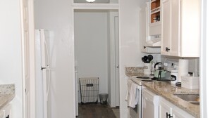 A kitchen with white cabinets, a granite countertop, a coffee maker, and a dish rack. - Blue Ridge Cozy Cabin with Full Mountain View (Blue Ridge)