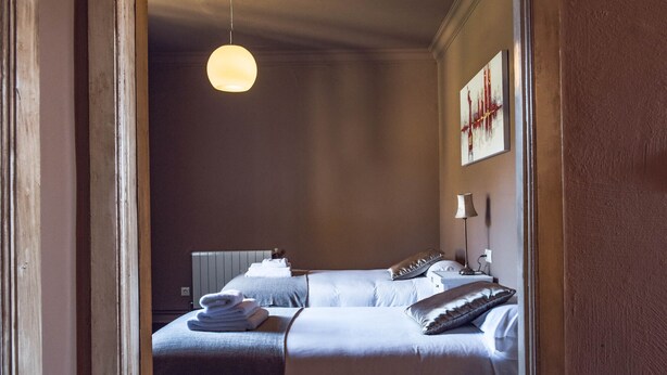 Een hotelkamer met twee bedden, een grote ronde lamp, een radiator en een schilderij aan de muur.