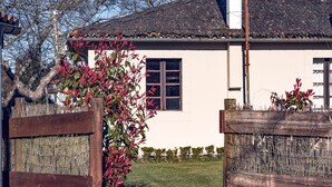 Een wit gebouw met rieten dak, een houten poort en een kleine tuin.