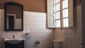 Een badkamer met een wastafel, spiegel, toilet en bad.