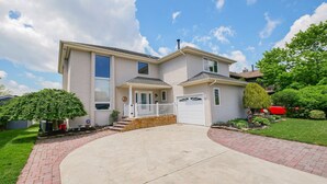 Ein zweistöckiges Haus mit Veranda, Garage und gepflegtem Rasen.