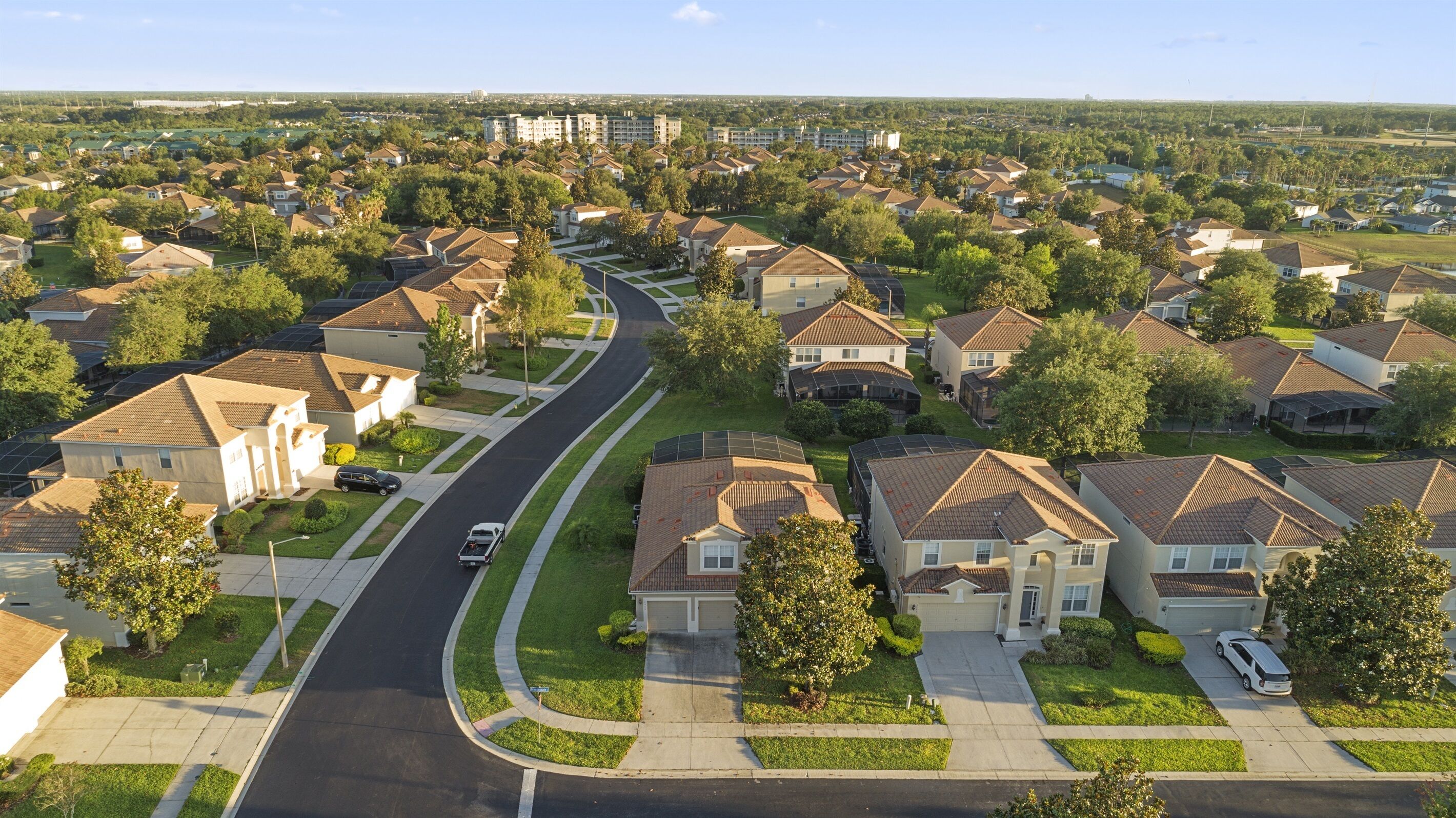 Un quartier résidentiel de banlieue, avec des maisons unifamiliales, une route sinueuse et un ciel dégagé.