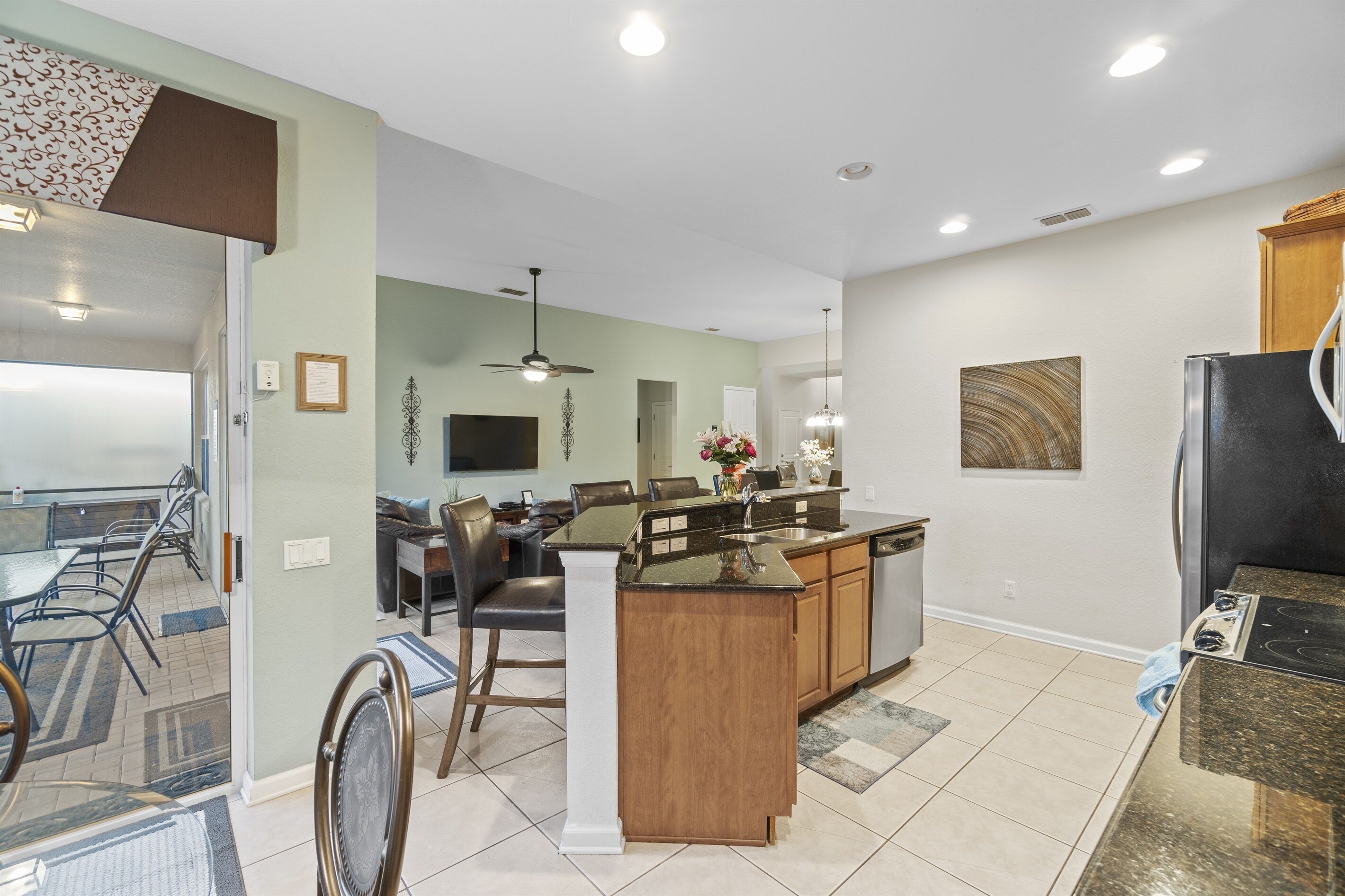 A modern kitchen with a central island, a dining area with a table and chairs, and a living room with a sofa and a TV.