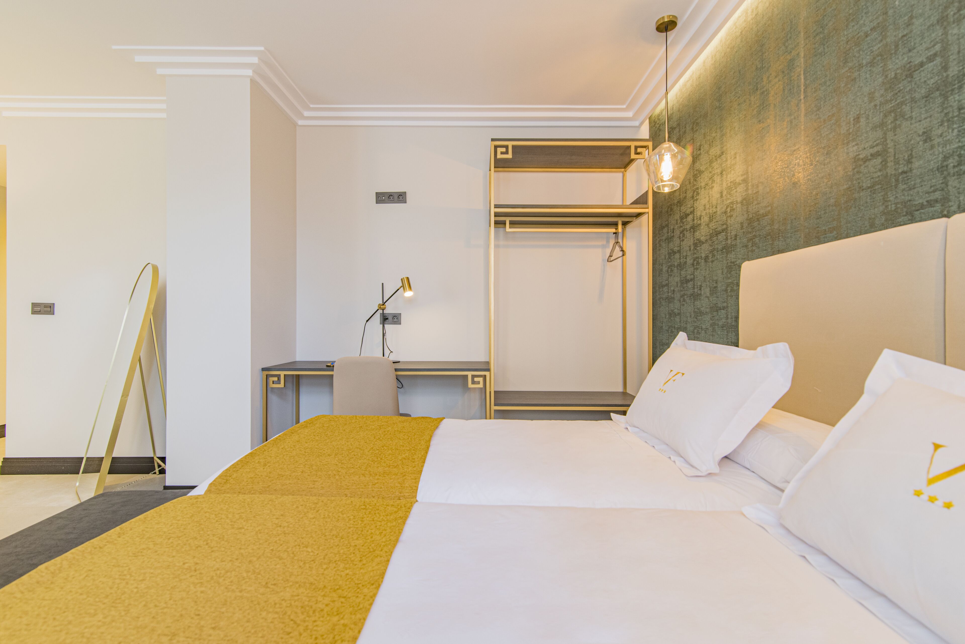 Una habitación de hotel con cama, escritorio, silla y espejo.