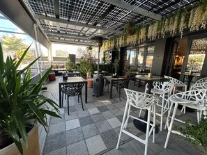 An outdoor patio with tables and chairs, potted plants, and a solar panel ceiling. - VESCI FAVENTIA (Huetor-Tajar)