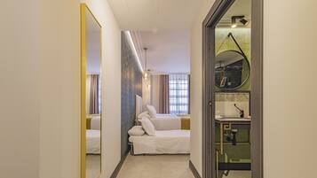 A hotel room with a bed, a bathroom with a sink and mirror, and a hallway with a mirror.