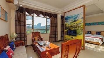 Habitación de hotel con cama, escritorio con computadora, sofá y vista al exterior.