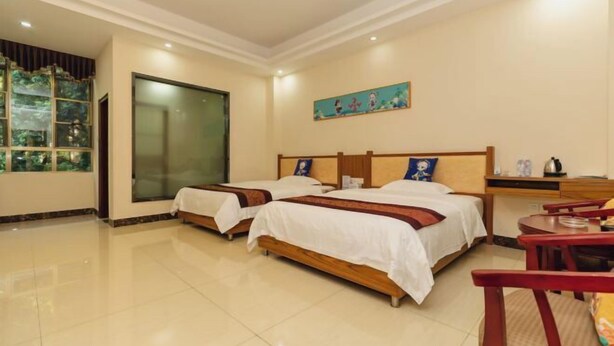 A hotel room with two beds, a large window, a painting on the wall, and a small table with chairs. - Qianyuanju Inn (Renhua)