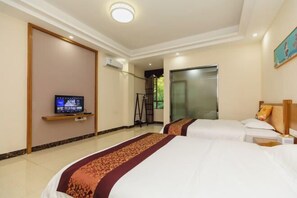 Une chambre d’hôtel avec deux lits, un téléviseur posé sur un meuble et une porte donnant sur un balcon.