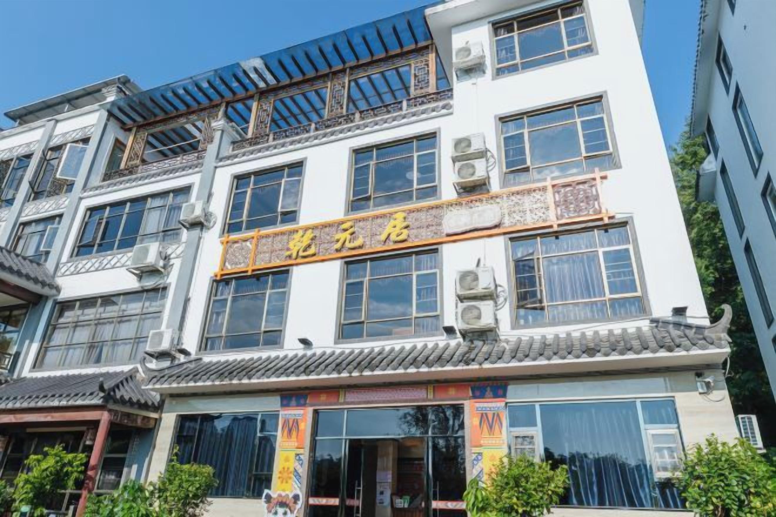 Ein mehrstöckiges Gebäude im traditionellen Stil, mit einer auffälligen Beschilderung in chinesischen Schriftzeichen, großen Fenstern und Klimaanlagen.