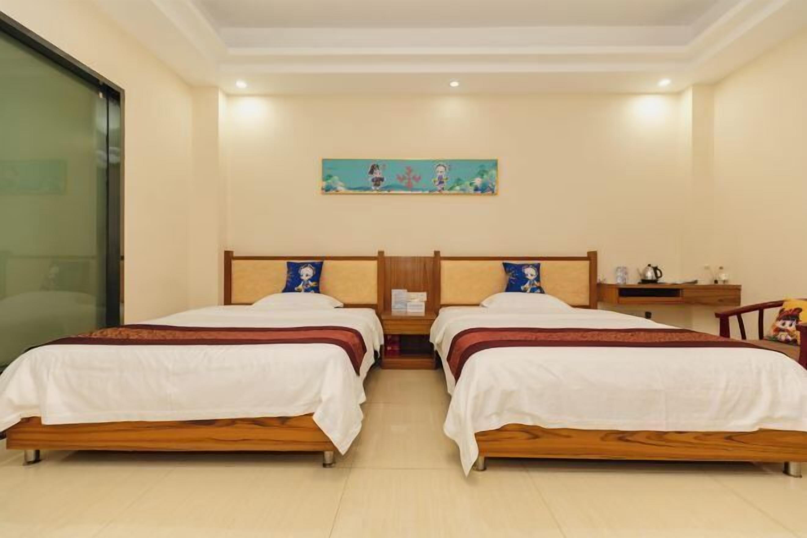 A hotel room with two wooden beds, a nightstand, a small table, and a painting on the wall.