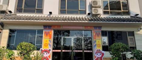 Un edificio con techo de tejas tradicionales, amplios ventanales y una entrada colorida adornada con banderines.