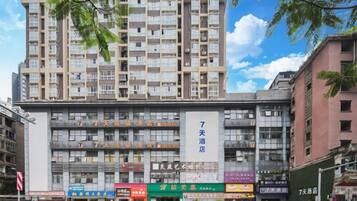 A multi-story building with a commercial ground floor, including various shops and a prominent sign for a hotel.