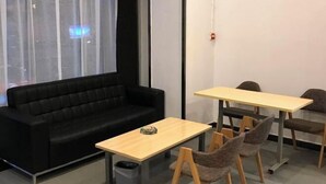 A modern room with a black sofa, two wooden tables, and four chairs. - 7Days Inn Chain Hotel (Chongqing Fuling Nanmenshan Pedestrian Street) (Chongqing)
