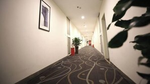 A hotel hallway with a patterned carpet, framed artwork on the walls, and potted plants. - 7Days Inn Chain Hotel (Chongqing Fuling Nanmenshan Pedestrian Street) (Chongqing)