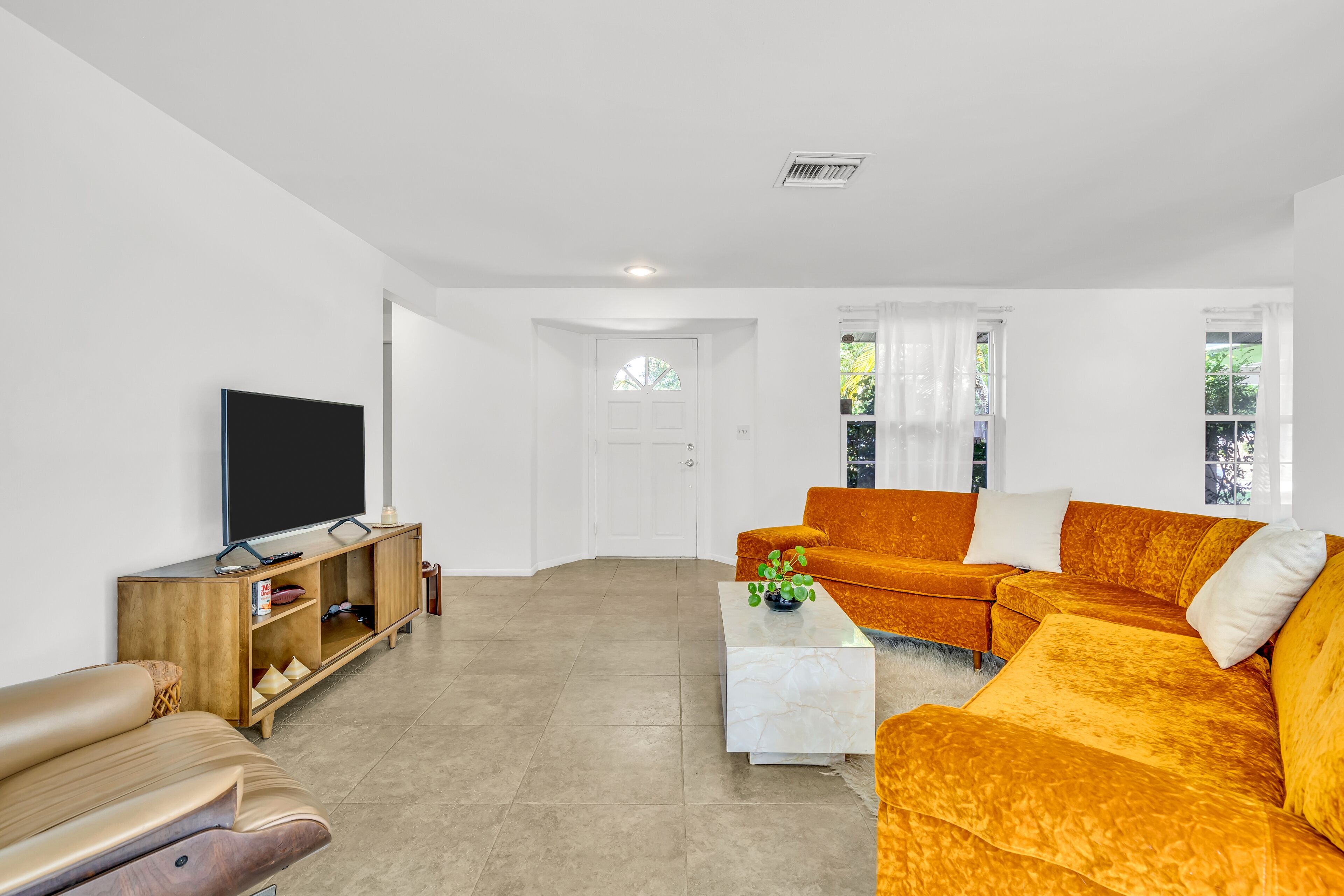 Una sala de estar moderna con un televisor de pantalla plana grande, un mueble de madera para entretenimiento, un sofá y una mesa de centro.