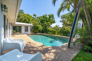 A swimming pool with a white chair and a small building in the background. - Private Mid Century Oasis 2mi to Beach with Pool (Sarasota)