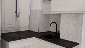 A kitchen with white cabinets, a black countertop, and a tiled backsplash. - Casa Isabella Monterosso (Monterosso al Mare)