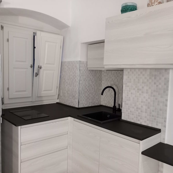 A kitchen with white cabinets, a black countertop, and a tiled backsplash.