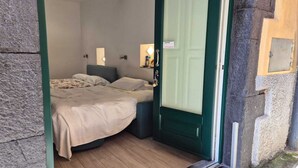 A small, cozy bedroom with a bed, bedside tables, and a door leading to another room. - Casa Isabella Monterosso (Monterosso al Mare)